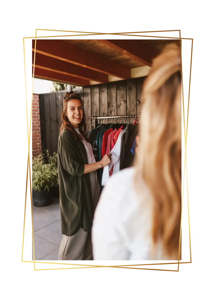 Stylist staat bij kledingrek en bespreekt outfits met klant op de voorgrond