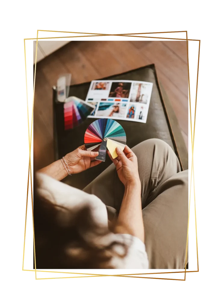 Persoon houdt een kleurenwaaier vast; op tafel ligt een inspiratiekaart met kleuren en voorbeelden.
